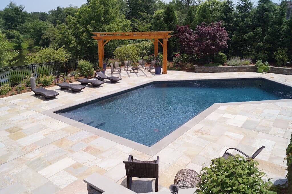 Landscaped pool area with stone pavers and plantings in New York