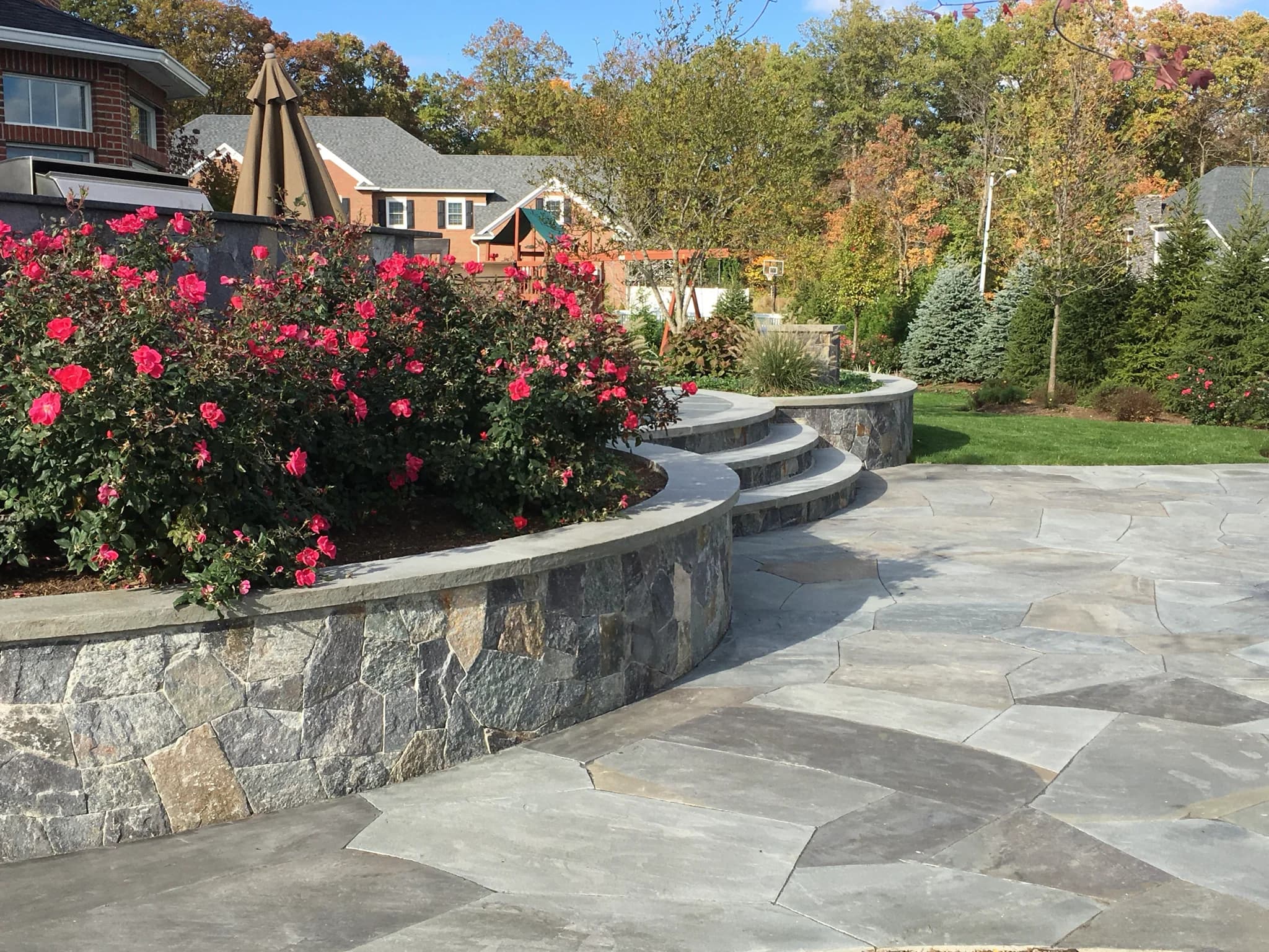 Stone patio and retaining wall with planted beds
