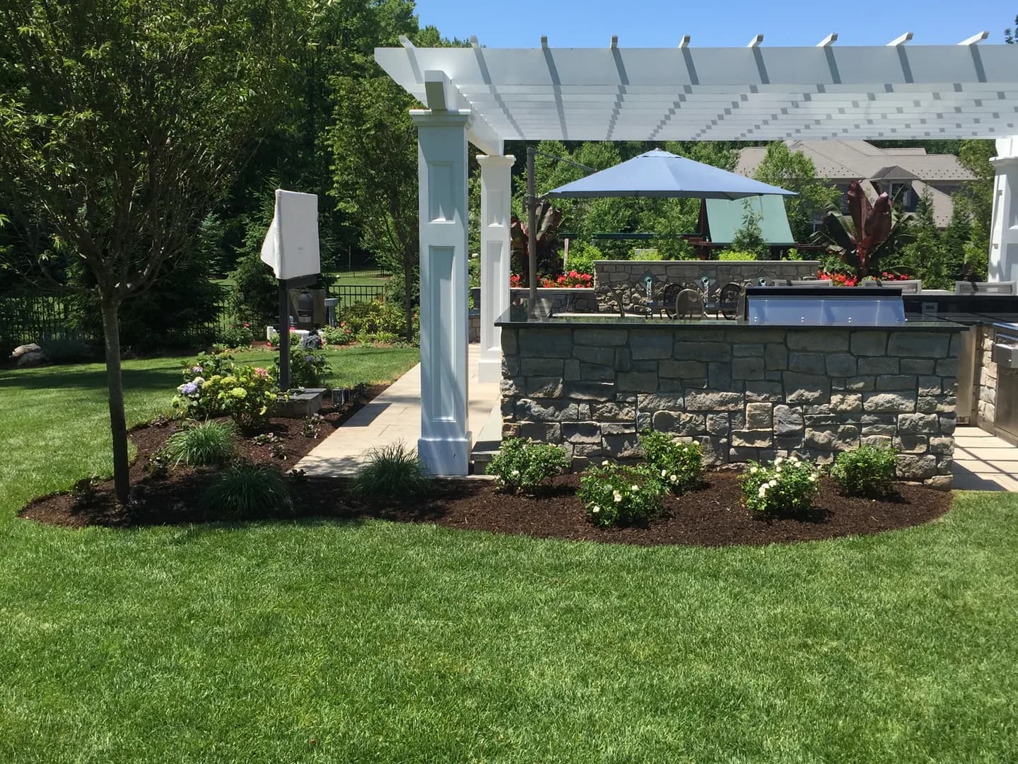 Outdoor kitchen and pergola with custom stonework