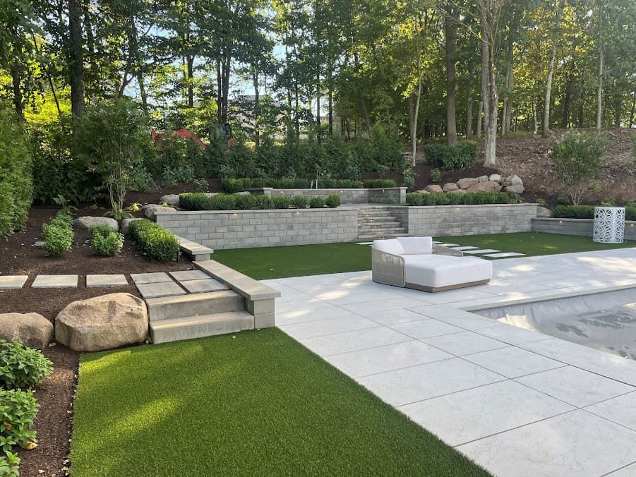 Tiered stone retaining wall with steps, turf, and a stone patio