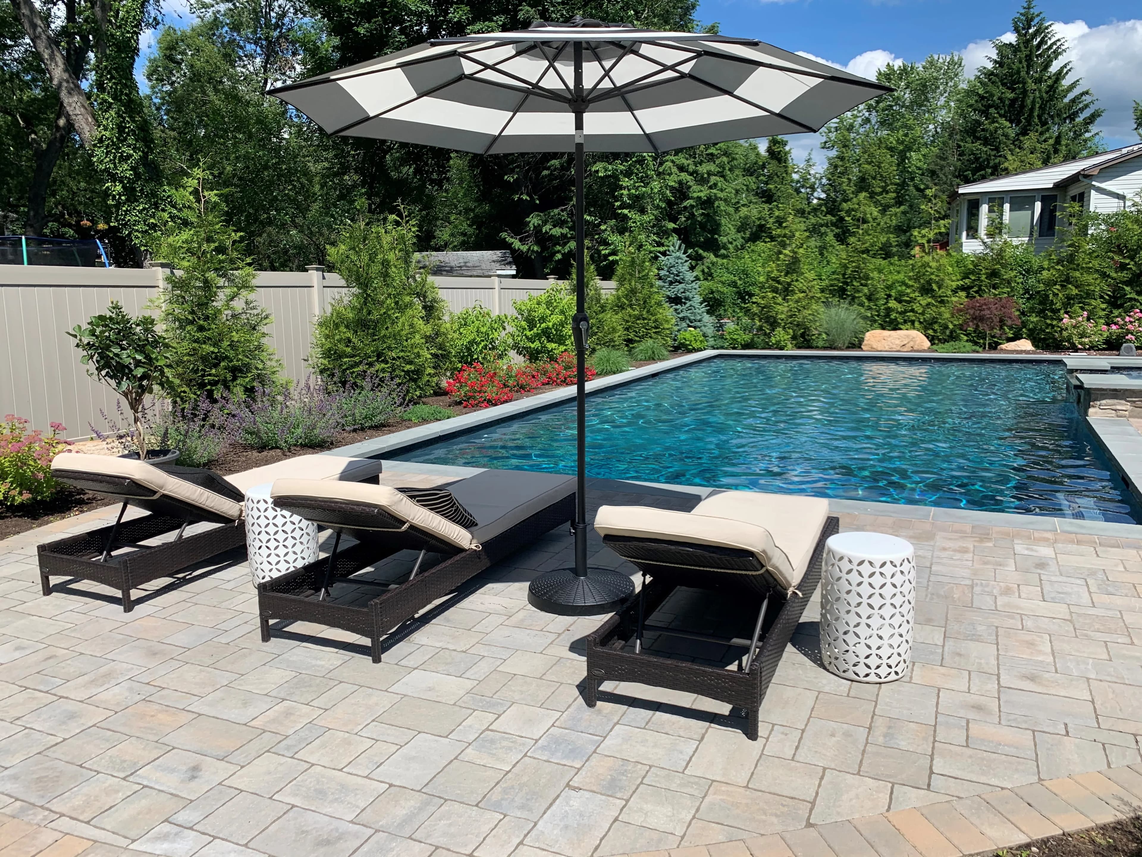 Poolside paver patio with loungers and a shade umbrella