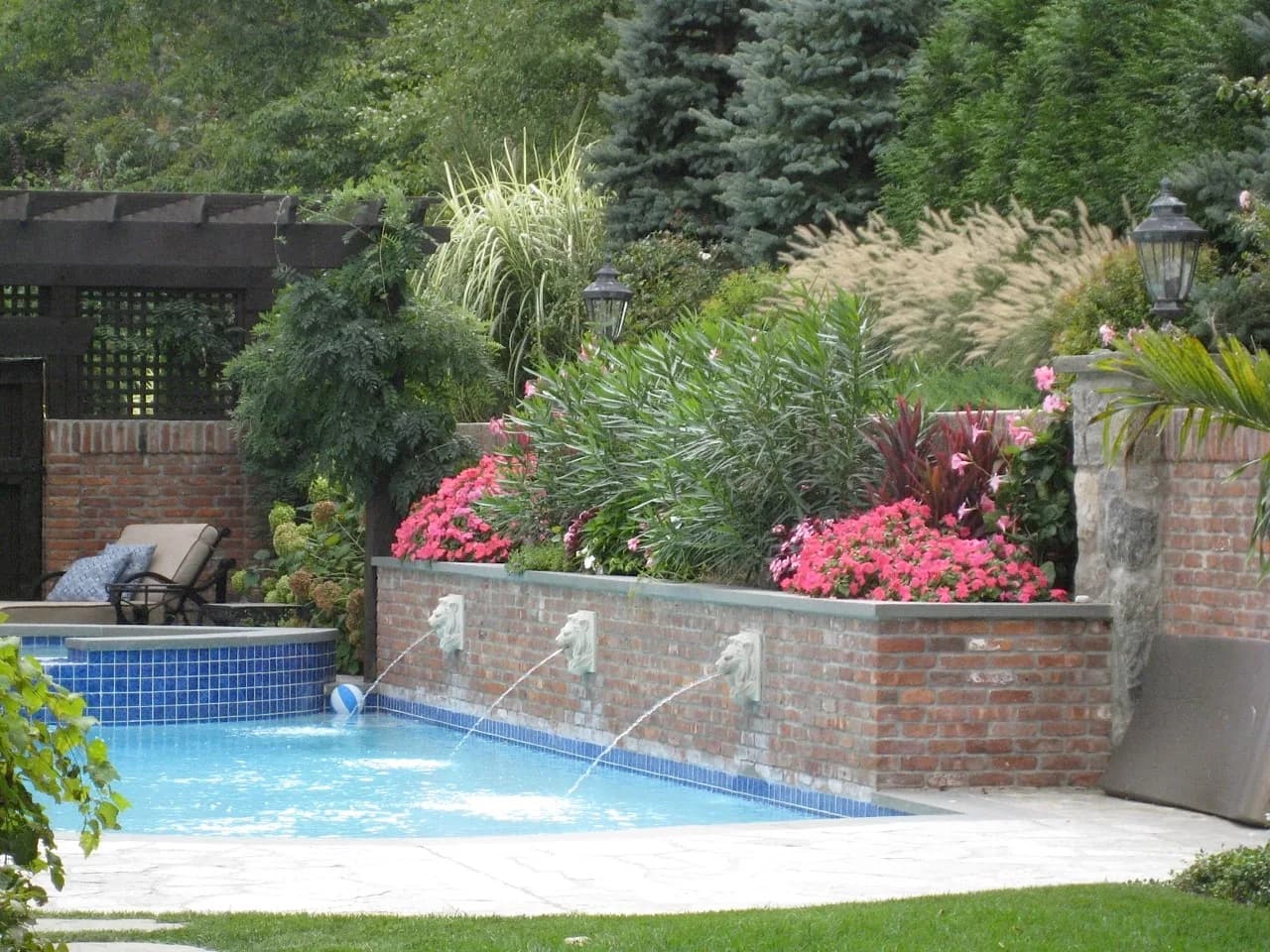 Swimming pool with a brick water feature wall and lion-head scuppers